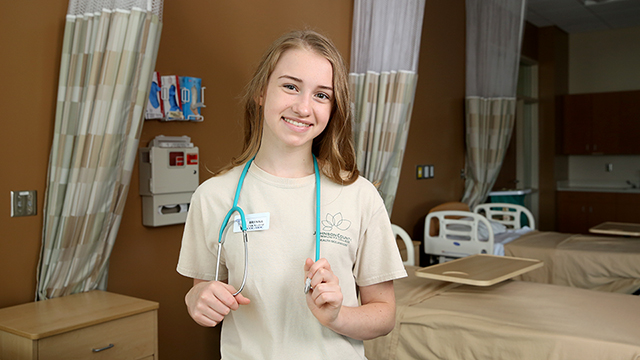 Early College student wearing C N A scrubs with a stethoscope around her neck